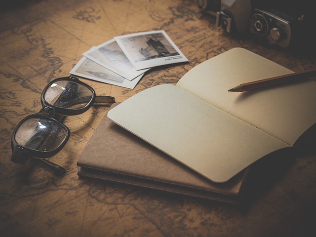 A notebook, a pen and eyeglasses on a study table.