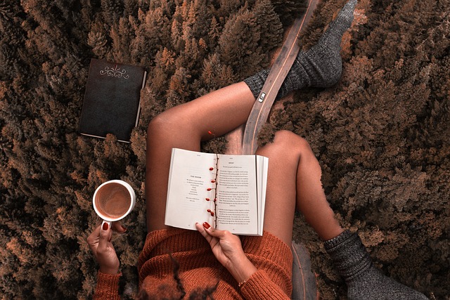 a woman on a rug reading a book and drinking coffee.